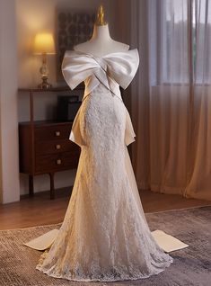 the back of a wedding dress on display in front of a window with drapes