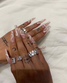 a woman's hands with pink and white nail polish on them, holding three different rings