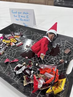 an elf is sitting on top of a table filled with candy bars and candies