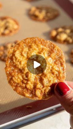 a person holding up a cookie in front of some cookies on a baking sheet with the video