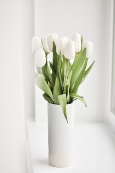 a white vase filled with lots of white flowers