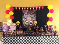 a table topped with lots of balloons and candy bar decorations in front of a black and white checkered table cloth