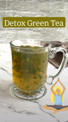 a glass cup filled with green tea sitting on top of a table