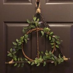 a wreath hanging on the front door of a house decorated with greenery and twine