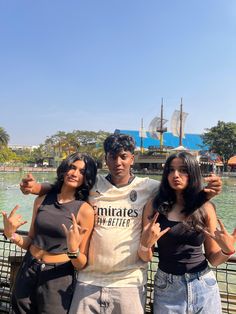 three people posing for the camera in front of a body of water