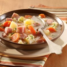 a bowl of soup with ham, potatoes and carrots