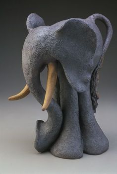 an elephant statue sitting on top of a white table next to a gray wall and floor