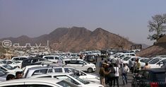 a parking lot full of cars with mountains in the backgrouds behind them