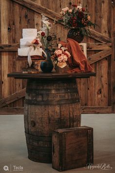 a wooden barrel with flowers on it and two small vases sitting on top of it