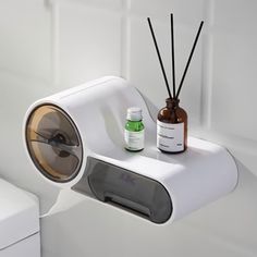 a white toilet sitting next to a wall mounted air freshener dispenser