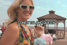 a woman in sunglasses holding up a sign with the words coney island queen on it