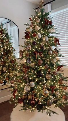 two christmas trees decorated with ornaments and lights