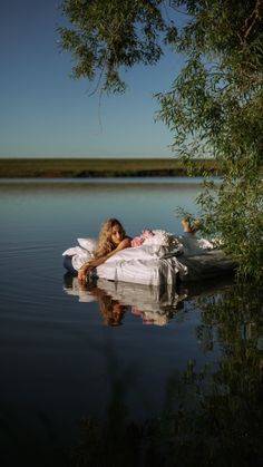 a woman laying on top of a bed in the middle of a body of water