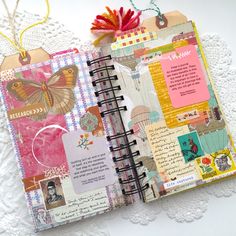 an open notebook with pictures and tags attached to the pages, sitting on a lace doily