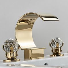 a gold faucet with three crystal knobs on the sides and a white wall behind it