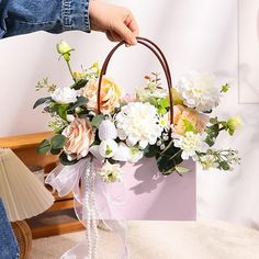 a person holding a pink bag with flowers in it