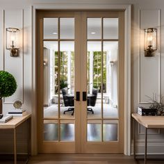 an office with two desks and glass doors leading to the sitting area in the room