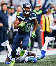 a football player running with the ball in his hand and people watching from the sidelines