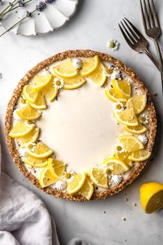 a pie with lemons on it sitting next to a knife and fork, surrounded by other food items