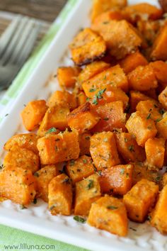 a white plate topped with cut up sweet potatoes and garnished with parsley