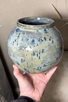 a hand holding a blue and yellow vase