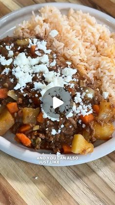 a white plate topped with rice and meat next to another plate filled with food on top of a wooden table