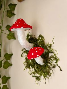 two mushrooms are sitting on the wall next to green plants and ivy growing up against it