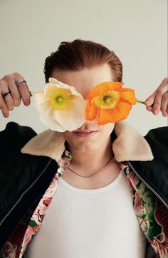 a woman holding two flowers in front of her face