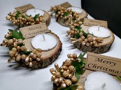 some candles are sitting on a table with merry christmas tags around them and pine cones