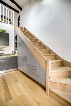 a kitchen with stairs leading up to the upper floor and an oven on the far side