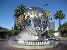 a large metal globe with the word las vegas on it in front of palm trees