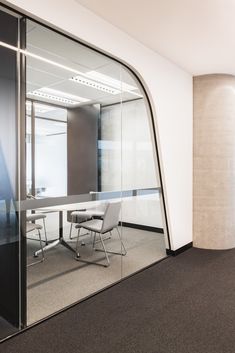 an empty office with glass walls and chairs