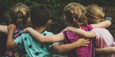 four children are hugging each other while sitting on a bench