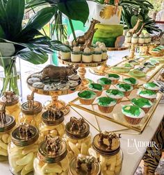 a table topped with lots of cupcakes covered in green frosting