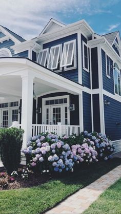 a blue and white house with flowers in the front yard