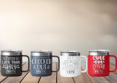 three different colored coffee mugs sitting on top of a wooden table next to each other