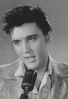 elvis presley singing into a microphone in an old black and white photo