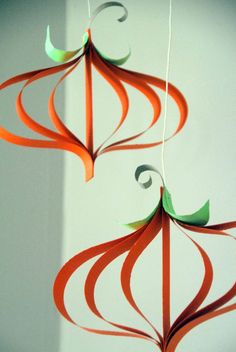 an orange and green mobile hanging on a wall next to a white wall in the background