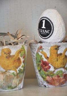 two decorated pots with eggs in them sitting on a table next to each other and one has a sticker that says 1 franc