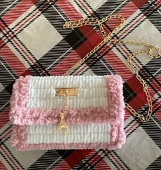 a pink and white purse sitting on top of a checkered tablecloth covered floor