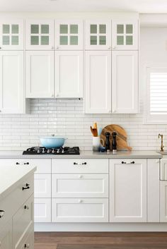 a kitchen with white cabinets and wood floors