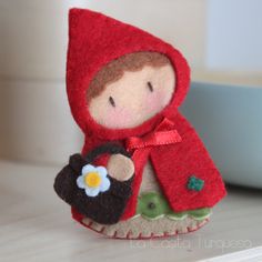 a little red hooded doll holding a flower