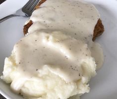 a plate with mashed potatoes and gravy on it next to a fork