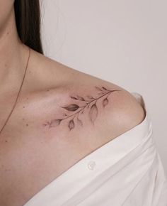 a woman wearing a white shirt has a tattoo on her chest