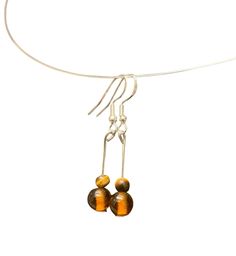 Elevate your style with these exquisite handmade silver drop earrings, featuring stunning amber and tiger's eye beads.  Each pair is meticulously crafted to showcase the natural beauty of the stones, making them the perfect accessory for any occasion. - High-quality sterling silver hooks and components - Genuine amber beads, known for their warm, golden hues - Authentic tiger's eye beads, admired for their striking bands of gold and brown - Length: Approximately 3cm (including hooks) - Bead size Cheap Amber Dangle Jewelry, Tiger Eye Beads, Eye Beads, Amber Beads, Tiger's Eye, Silver Drop Earrings, Unique Charms, Tiger Eye, Sterling Silber