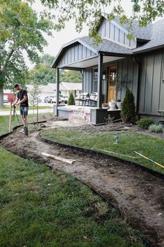 a man standing in front of a house holding a shovel and working on the ground