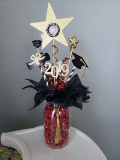 a glass jar filled with red and black confetti next to a gold star