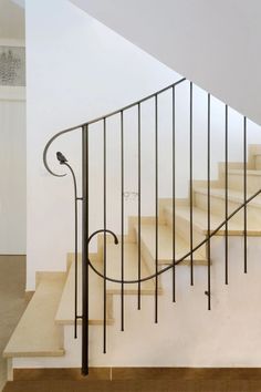 a bird is sitting on the handrail of a stair case in an empty room