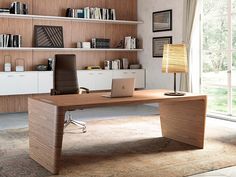 an office desk with a laptop on it in front of a book shelf filled with books