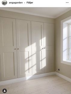 an empty room with white cupboards and windows